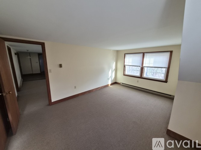 A room with a carpeted floor and a window with blinds.
