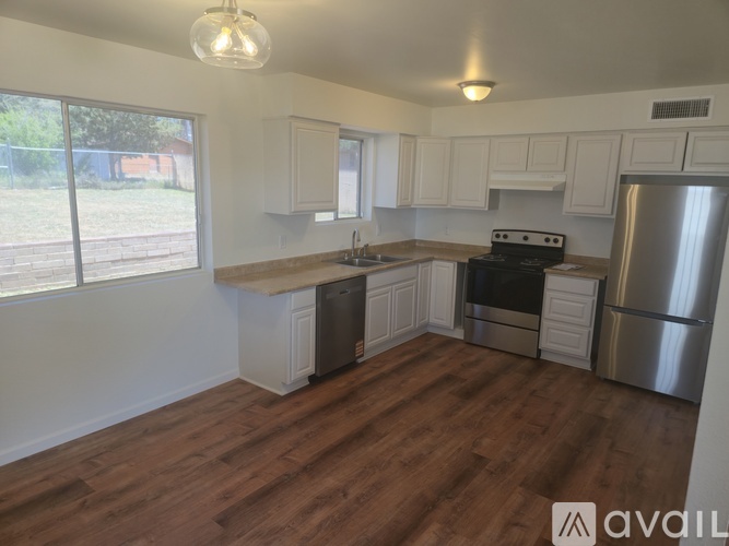 A kitchen with white cabinets and a wooden floor.
