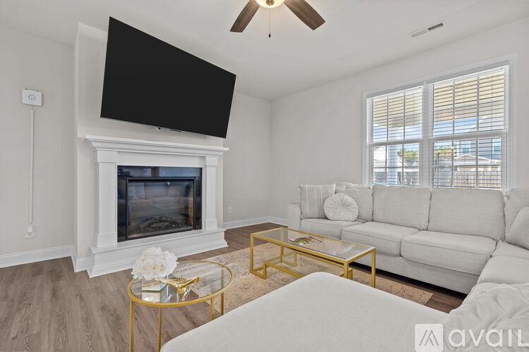 A living room with a white couch, a fireplace, and a television mounted above it.