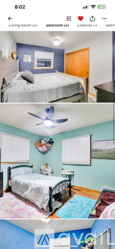 A bedroom with a bed, a ceiling fan, and a window.