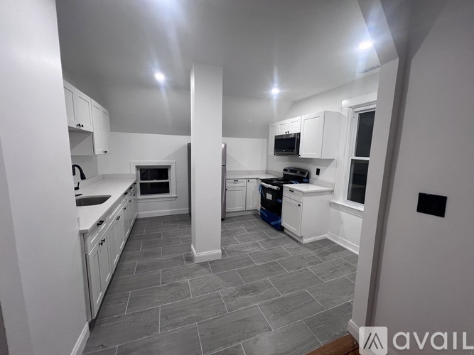 A kitchen with white cabinets and a grey floor.