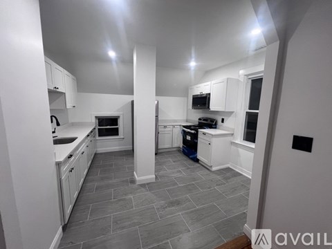 A kitchen with white cabinets and a grey floor.