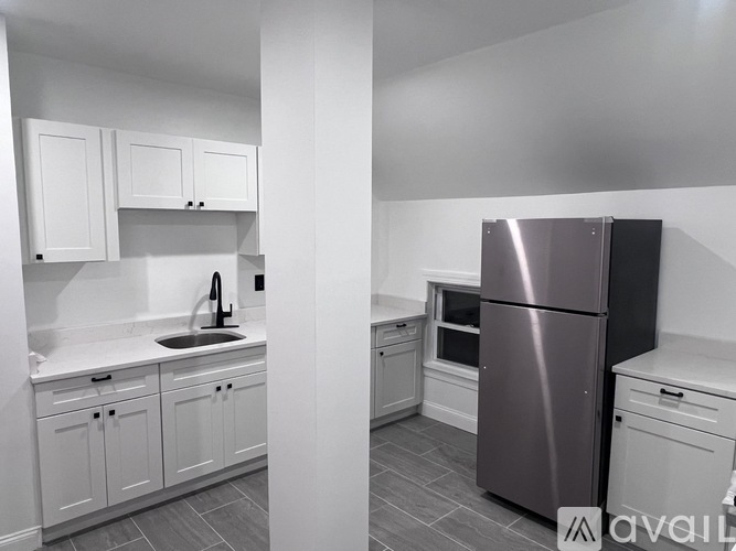 A kitchen with white cabinets and a stainless steel refrigerator.