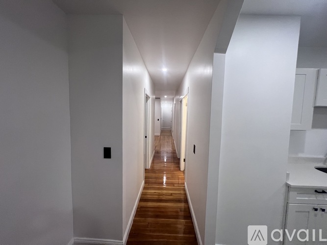 A long hallway with a wooden floor and white walls.