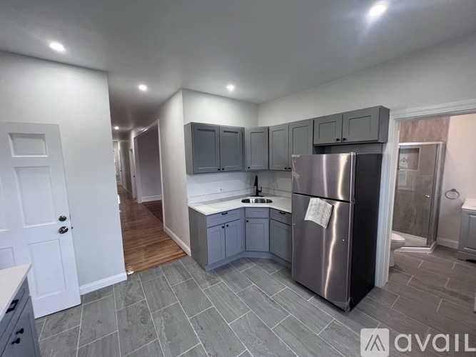 A kitchen with a refrigerator, sink, and cabinets.