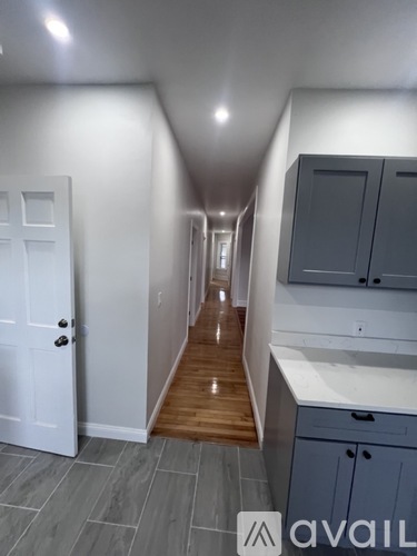 A hallway with a white door and a wooden floor.