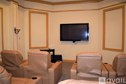 A living room with a television and leather chairs.