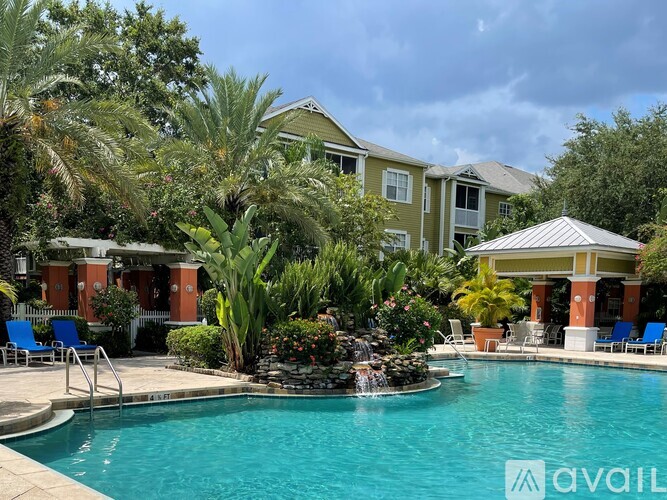 A pool surrounded by a patio with chairs and a house in the background.