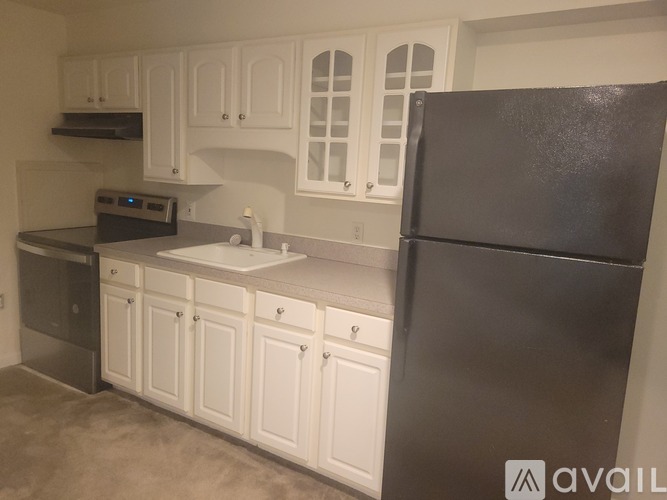 A kitchen with white cabinets and a black refrigerator.
