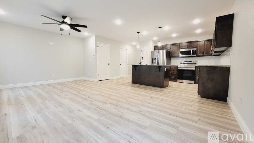 A spacious room with a kitchenette and a ceiling fan.