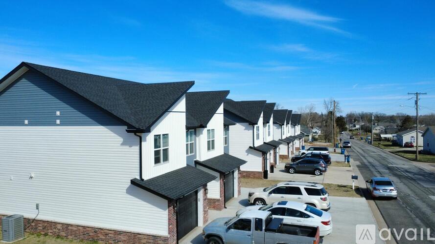 A row of houses with cars parked in front.