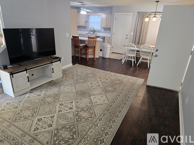 A living room with a rug on the floor and a television on the left side.
