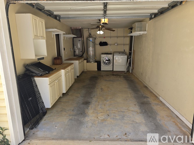 A garage with a fan, a washer and a dryer.