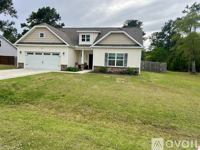 A two-story house with a garage is surrounded by a grassy yard.