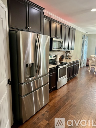 A kitchen with a stainless steel refrigerator and wooden floors.