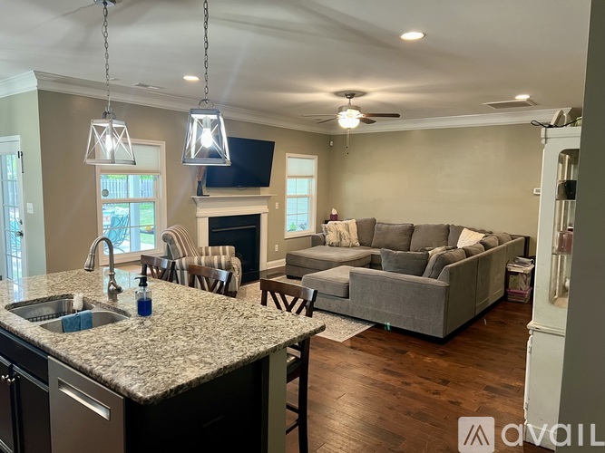 A modern kitchen with a granite countertop and a grey sofa in the living room.