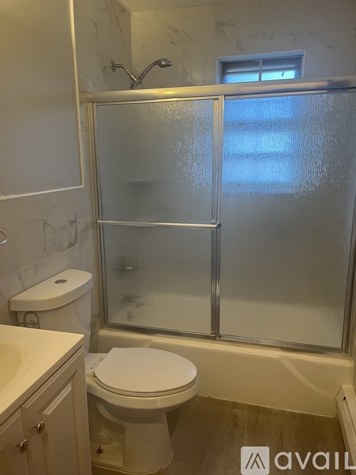 A bathroom with a toilet, sink, and frosted glass shower door.