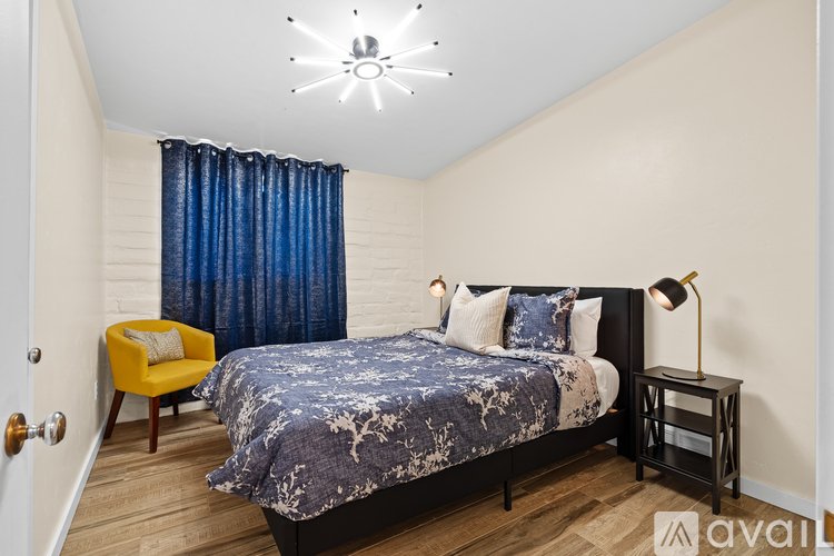 A bedroom with a bed, yellow chair, and blue curtains.