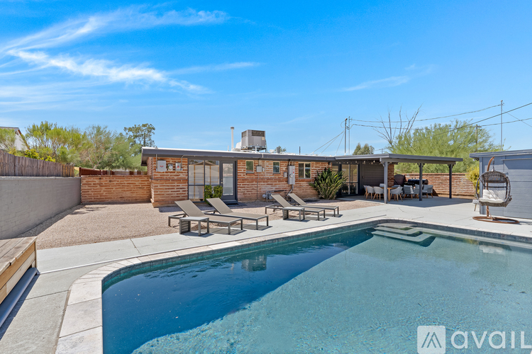 A pool in a backyard with a patio and a house in the background.