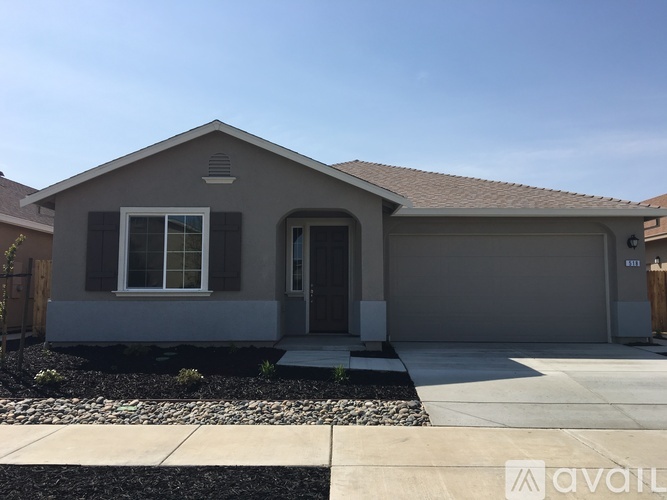 A house with a grey front yard and a brown door.