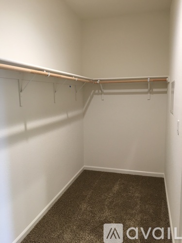 A room with a carpeted floor and a coat rack.