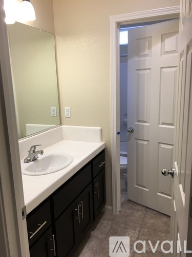 A bathroom with a sink, mirror, and black cabinets.