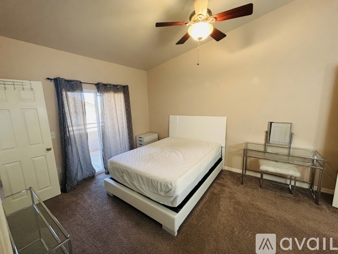 A bedroom with a bed, a fan, and a small table.