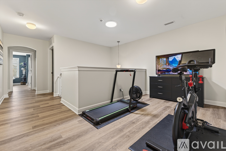 A home gym with a treadmill, exercise bike, and television.