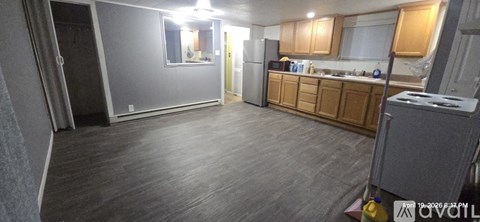 A kitchen area with wooden cabinets and a grey floor.