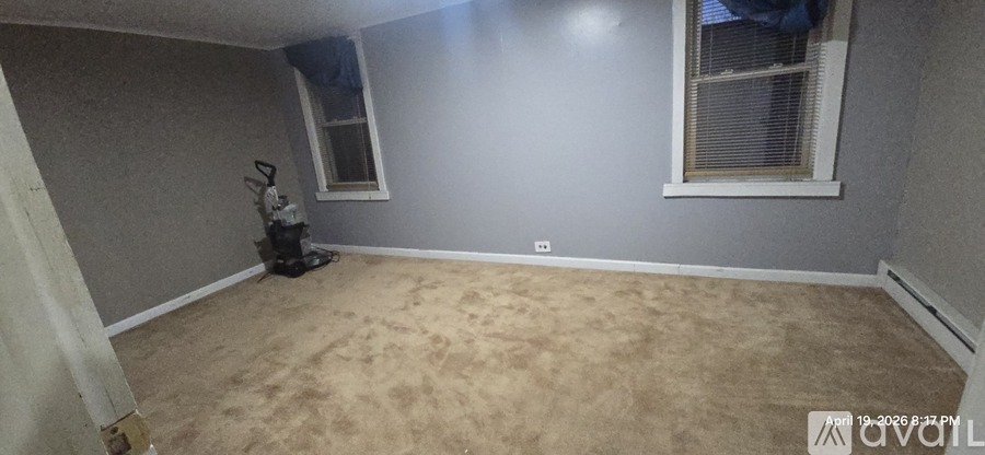 A room with a carpeted floor and a vacuum cleaner.