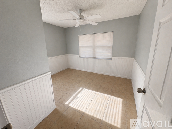 A room with a ceiling fan and a window with blinds.