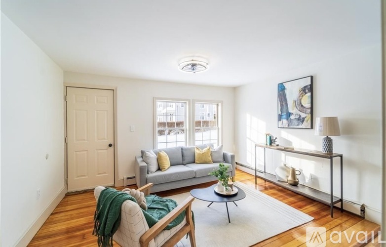 A living room with a couch, a chair, and a table with a plant on it.
