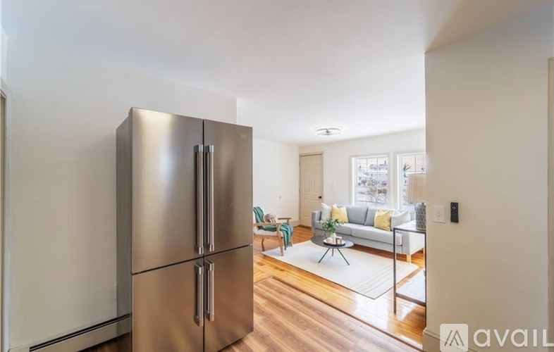 A modern kitchen with a stainless steel refrigerator and a living room with a couch and a coffee table.
