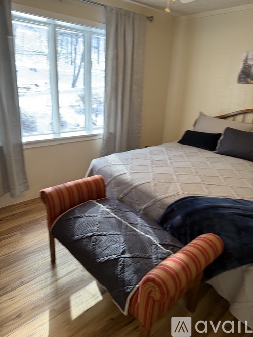 A bedroom with a bed and a chair.