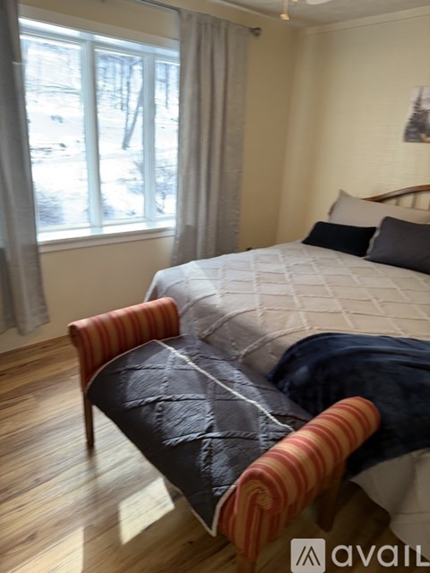 A bedroom with a bed and a chair.