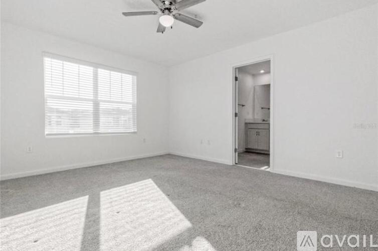 A spacious room with a ceiling fan and a doorway leading to another room.