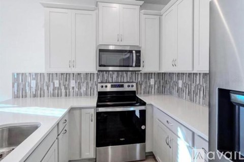 A kitchen with white cabinets and a black stove top oven.