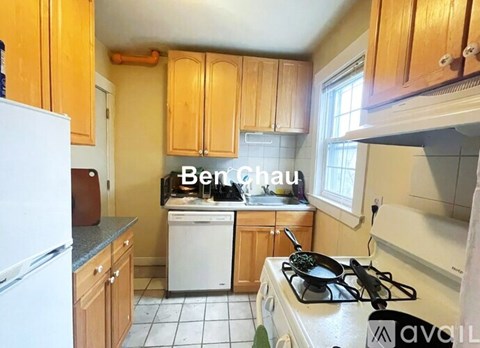 A kitchen with a white fridge, a white dishwasher, and wooden cabinets.