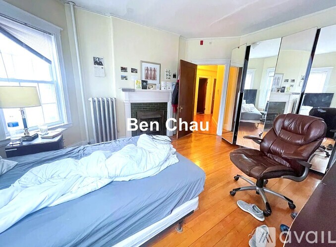 A bedroom with a bed, a chair, and a fireplace.