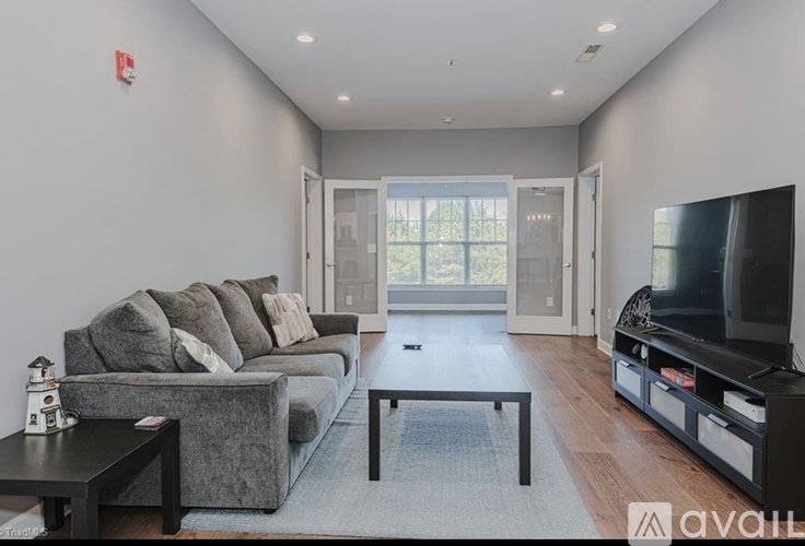 A living room with a grey couch, a black coffee table, and a flat screen TV.