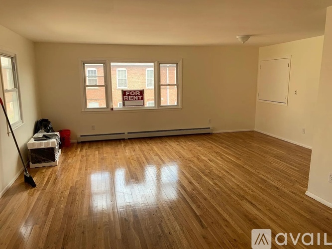 A room with wooden flooring and a window that says "FOR RENT".