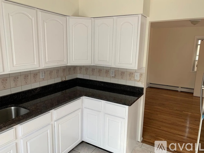 A kitchen with white cabinets and a black counter top.