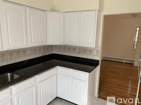 A kitchen with white cabinets and a black counter top.