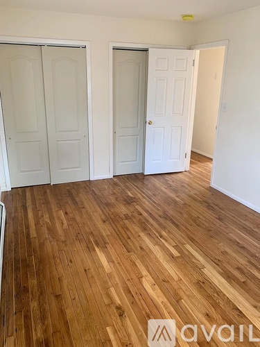 A room with wooden flooring and three doors.