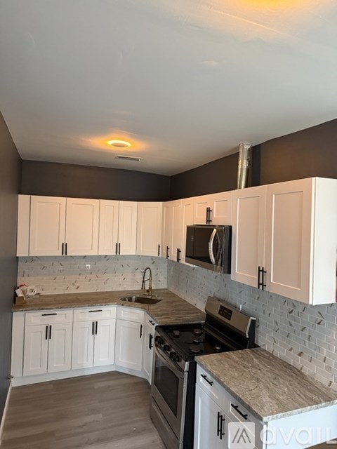 A kitchen with white cabinets and a tiled backsplash.