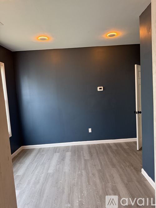 A room with a dark blue wall and a light wooden floor.