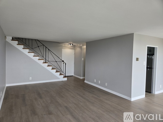 A spacious room with a staircase and a door on the right side.