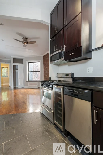 A modern kitchen with dark wood cabinets and stainless steel appliances.