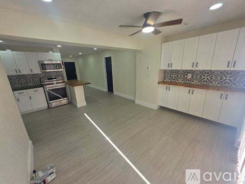 A spacious kitchen with white cabinets and a fan.