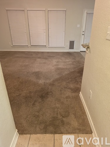 A room with a carpeted floor and a door with a white frame.